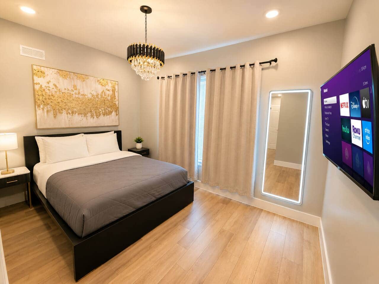 master bedroom featuring a comfortable queen-size bed, elegant décor, Tv, lit mirror, and a relaxing atmosphere for a restful night’s sleep. Enjoy the convenience of two separate his-and-her closets, providing ample storage space for longer stays.