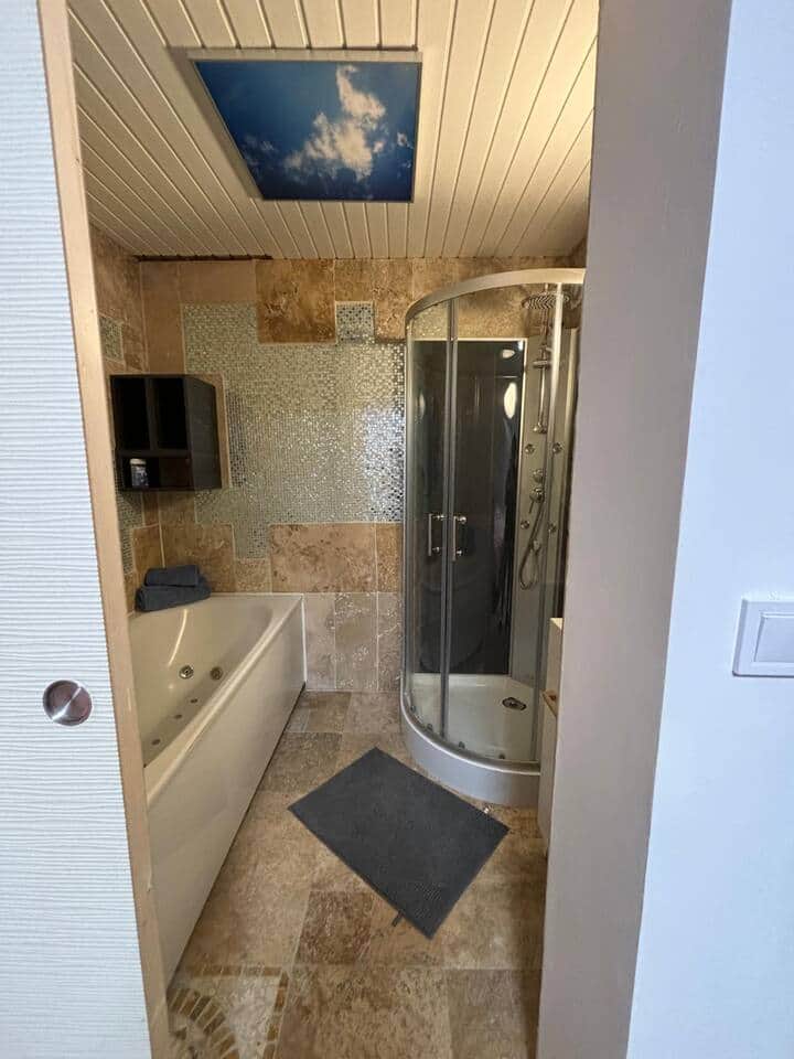 Salle de bain avec baignoire balnéo et douche.