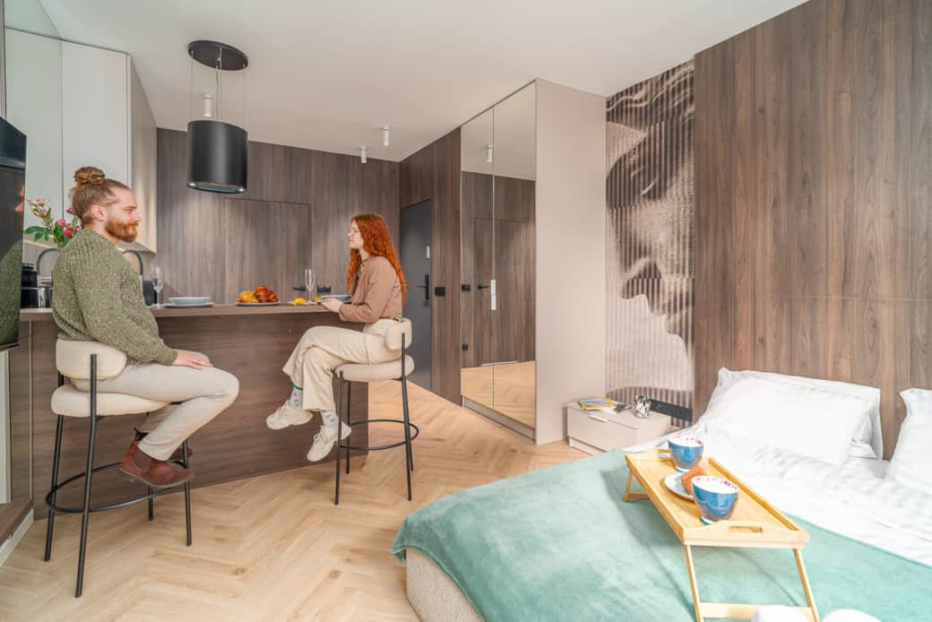 Modern studio with wooden cabinetry, comfy bed and dining island.