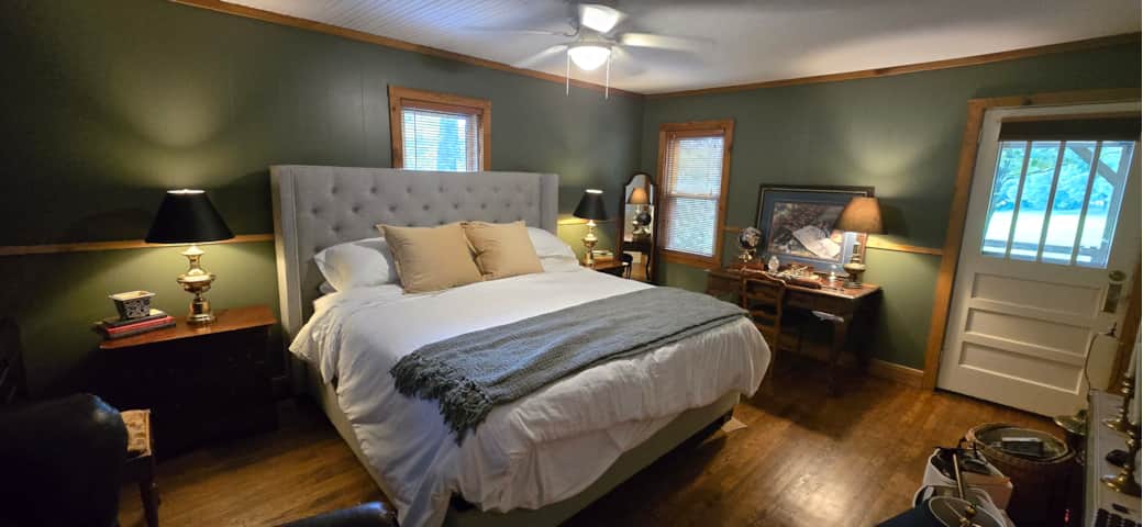 Largest bedroom with King bed, reading chair, work desk, and electric fireplace.