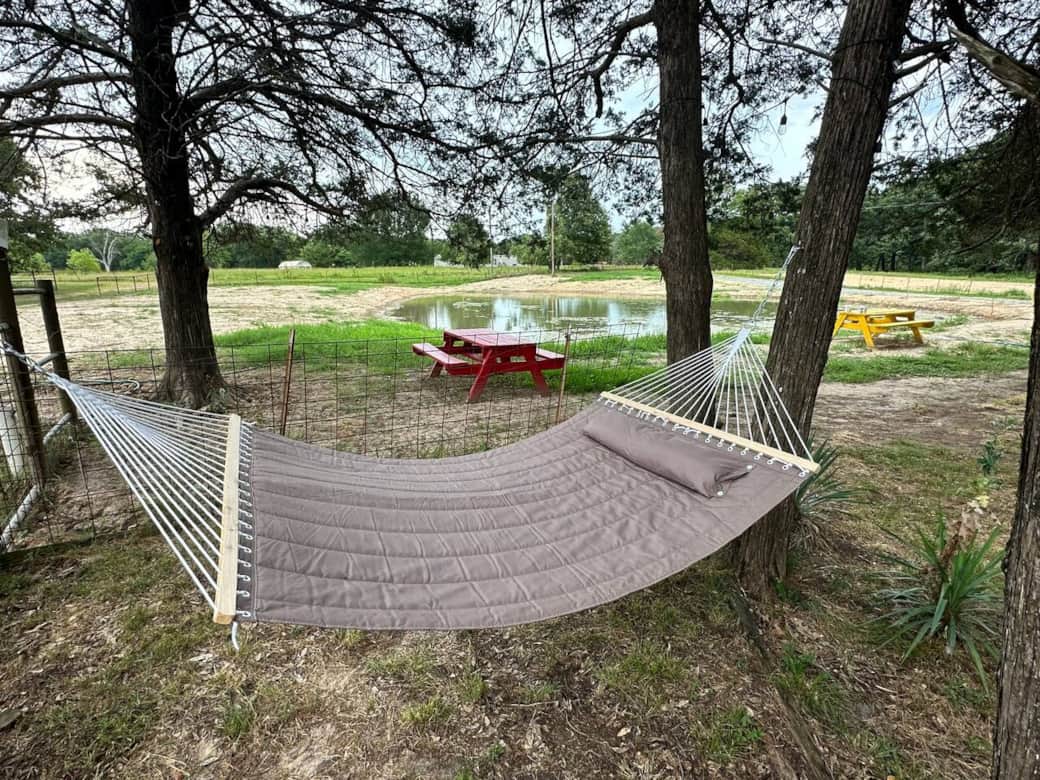 “Unwind in a cozy hammock tucked beneath shady trees, overlooking the peaceful pond. It’s the perfect spot to sip your morning coffee, read a book, or simply relax while listening to the sounds of nature.”