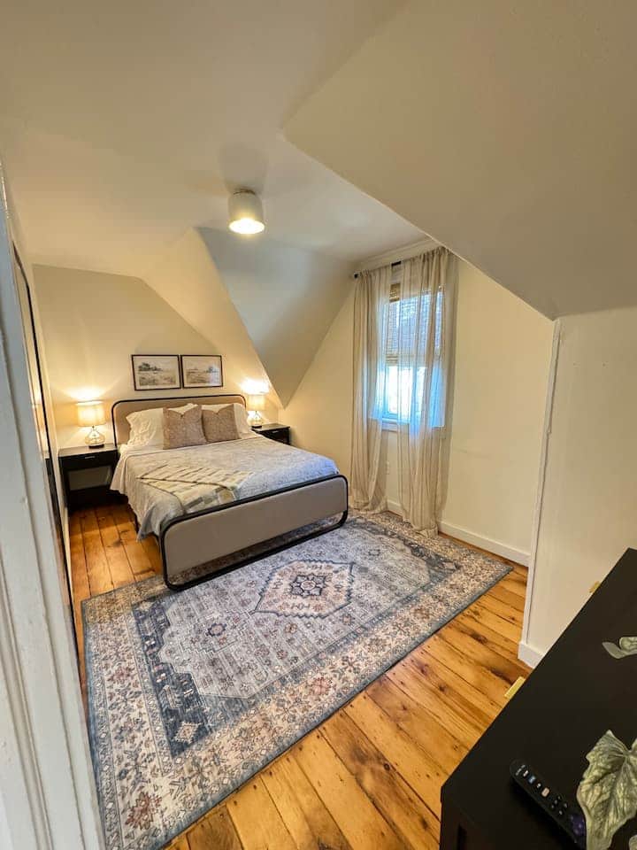 Cozy and inviting bedroom with warm hardwood floors, soft lighting.