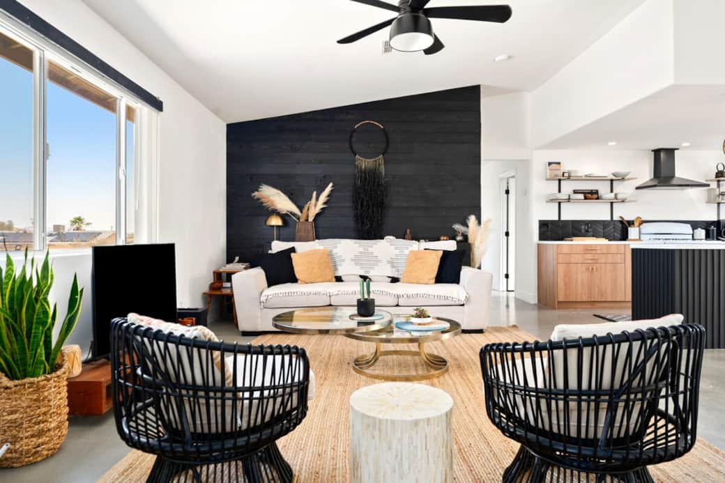Upon arrival: a stylish yet comfortable living room featuring a black accent wall, designer seating, and sunlit desert views — the perfect balance of cozy and chic.
