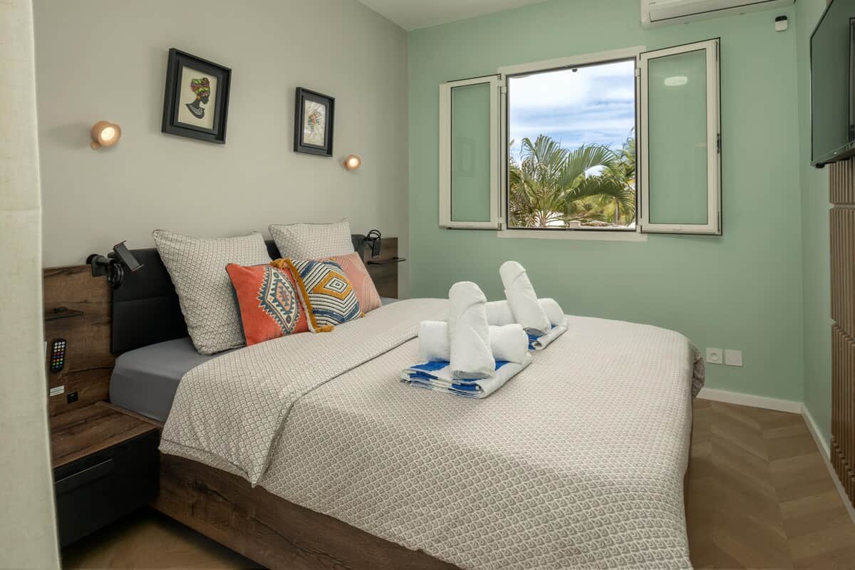 Chambre avec lit, accès véranda et vue sur les palmiers