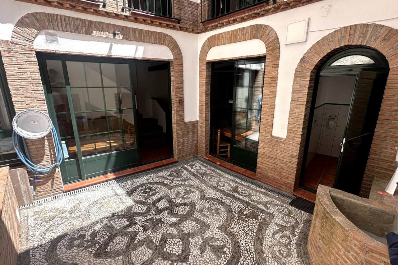 Patio empedrado con mosaico y galería acristalada