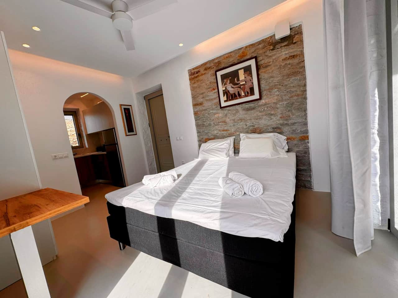 Double bedroom with stone feature wall and arched doorway, stone lodgings, Kea