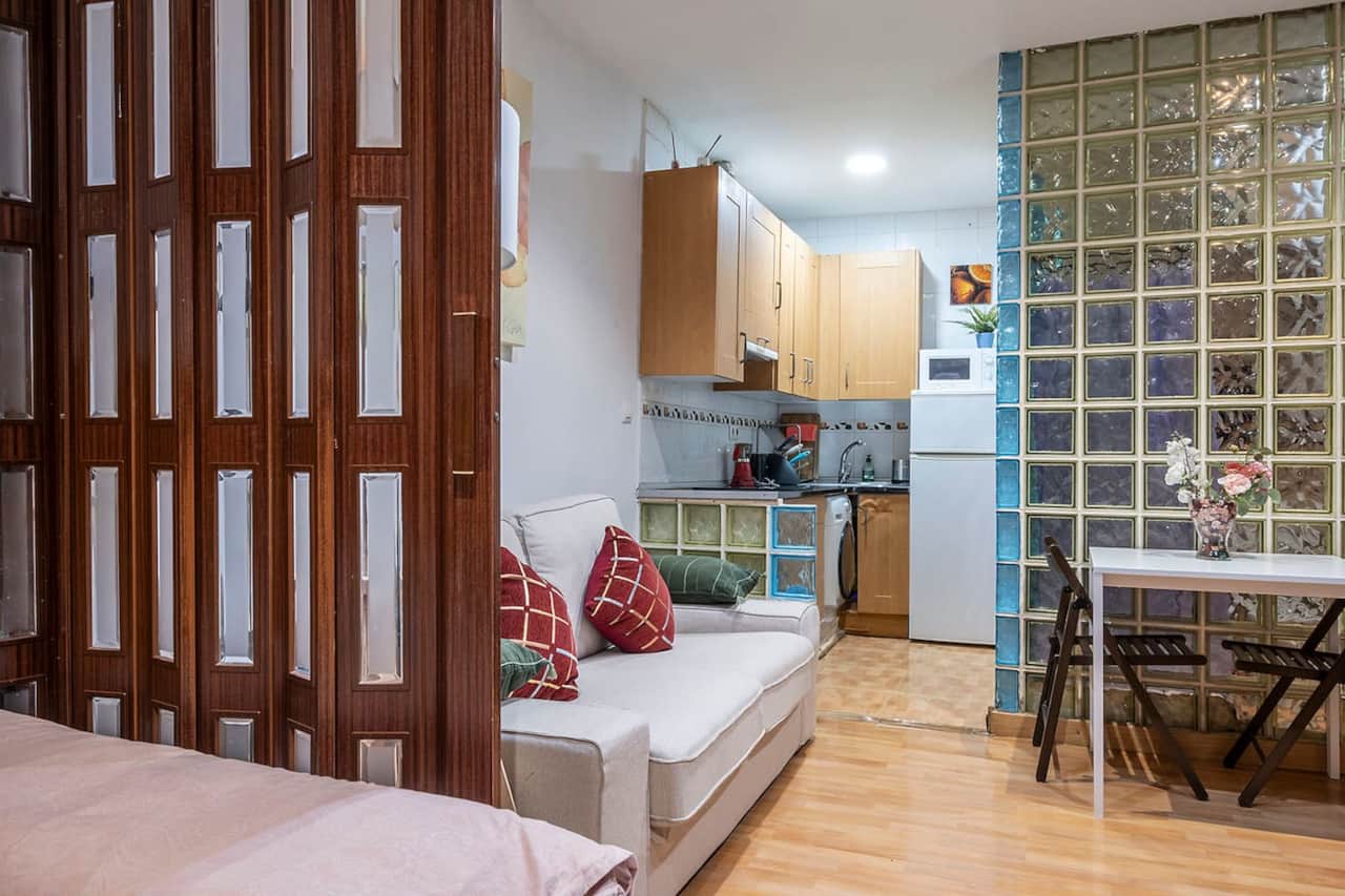 Salón con sofá, cocina y pared de pavés