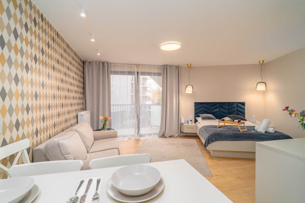 Nowoczesne studio z balkonem, dużym łóżkiem i częścią wypoczynkową.