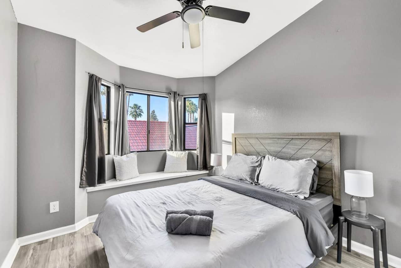 Secondary bedroom with a queen bed, ceiling fan, and a built-in window seating.