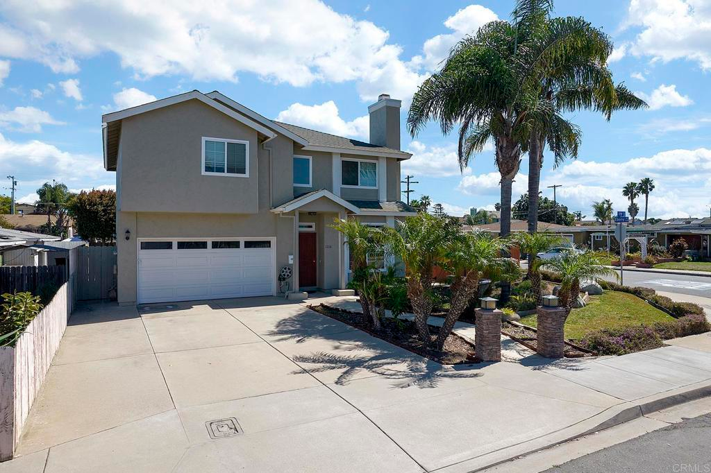 Welcoming two-story home with tropical landscaping and a spacious driveway.