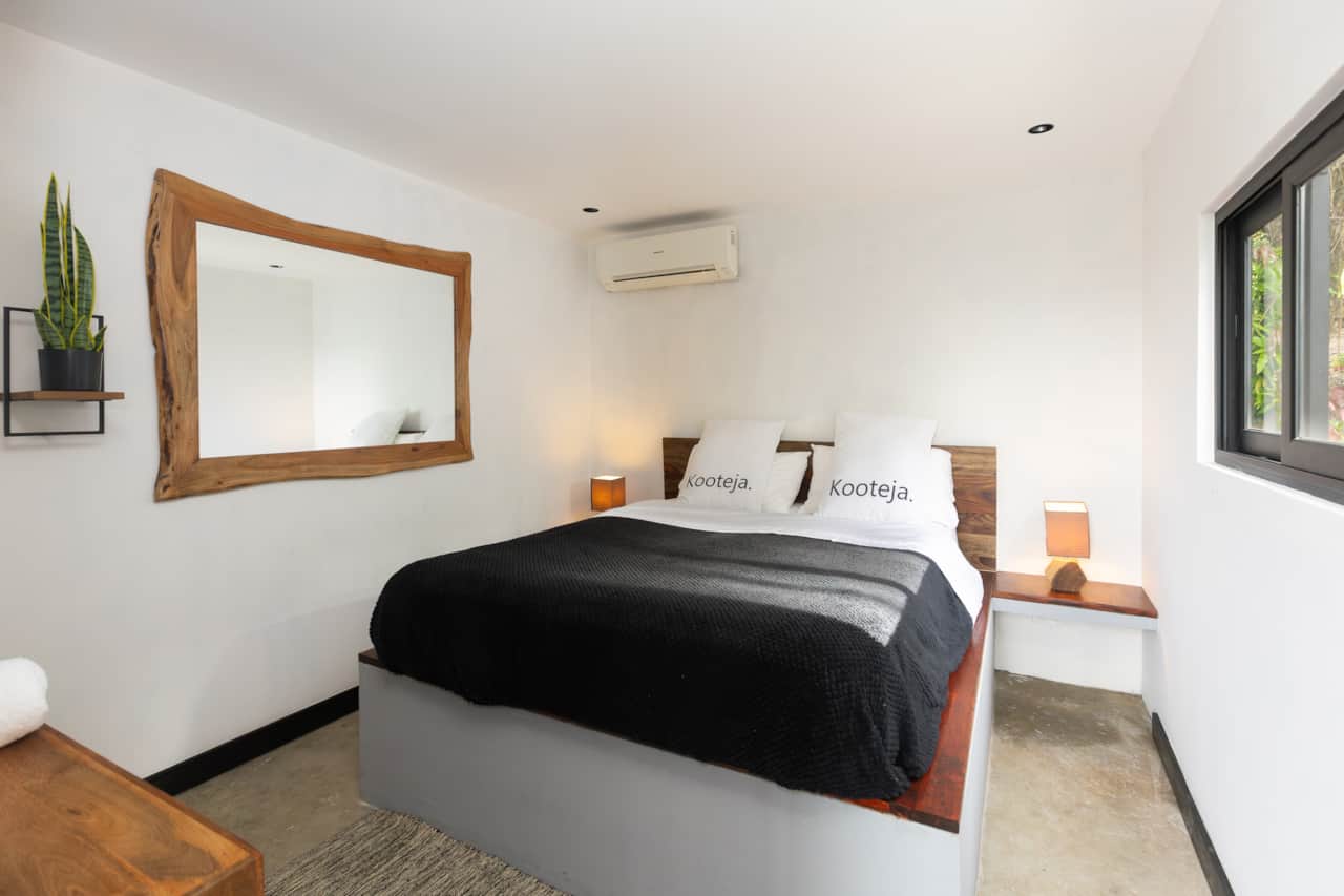 Clean lines and a natural edge mirror highlight this minimalist eco cabin Panama bedroom