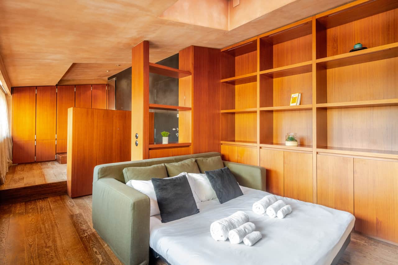 Dormitorio con cama y mueble de pared de madera, en Brera, Milán