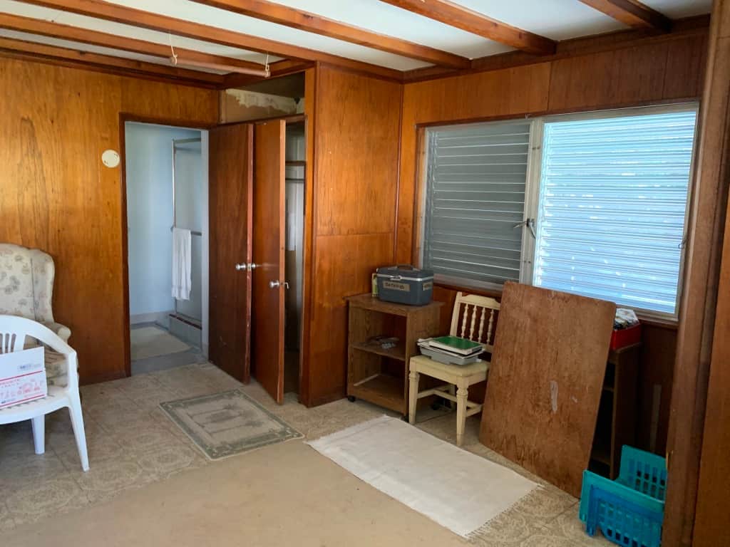Unit 3 at Casa Citron before renovation, showing extensive wood paneling and poor space planning with a bathroom door opening into a closet door, highlighting the need for functional reconfiguration.