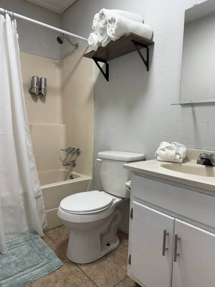 Full bathroom with necessary amenities like towels, toilet paper, hand soap, shampoo, conditioner and small body soap bars. 