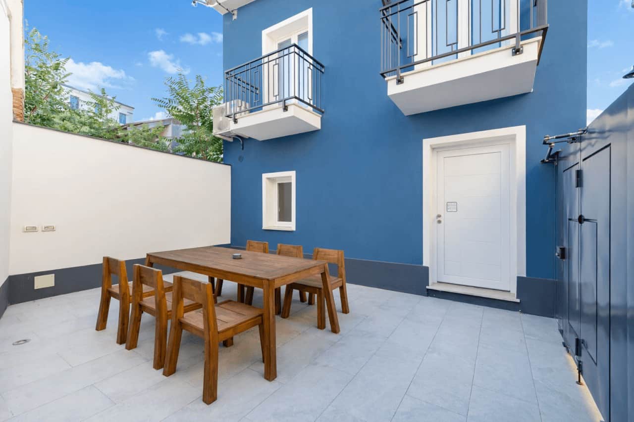 Via delle Terme 19 Olbia — private courtyard with outdoor dining and distinctive blue facade, long-term rental property via nr12 by RENTAL12, Sardinia