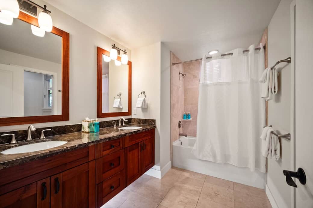 Second bathroom with dual vanity, shower/tub combo, and wood-framed mirrors