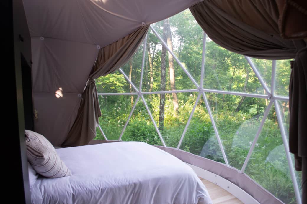 Panoramic window in front of queen bed with scenic view into the forest