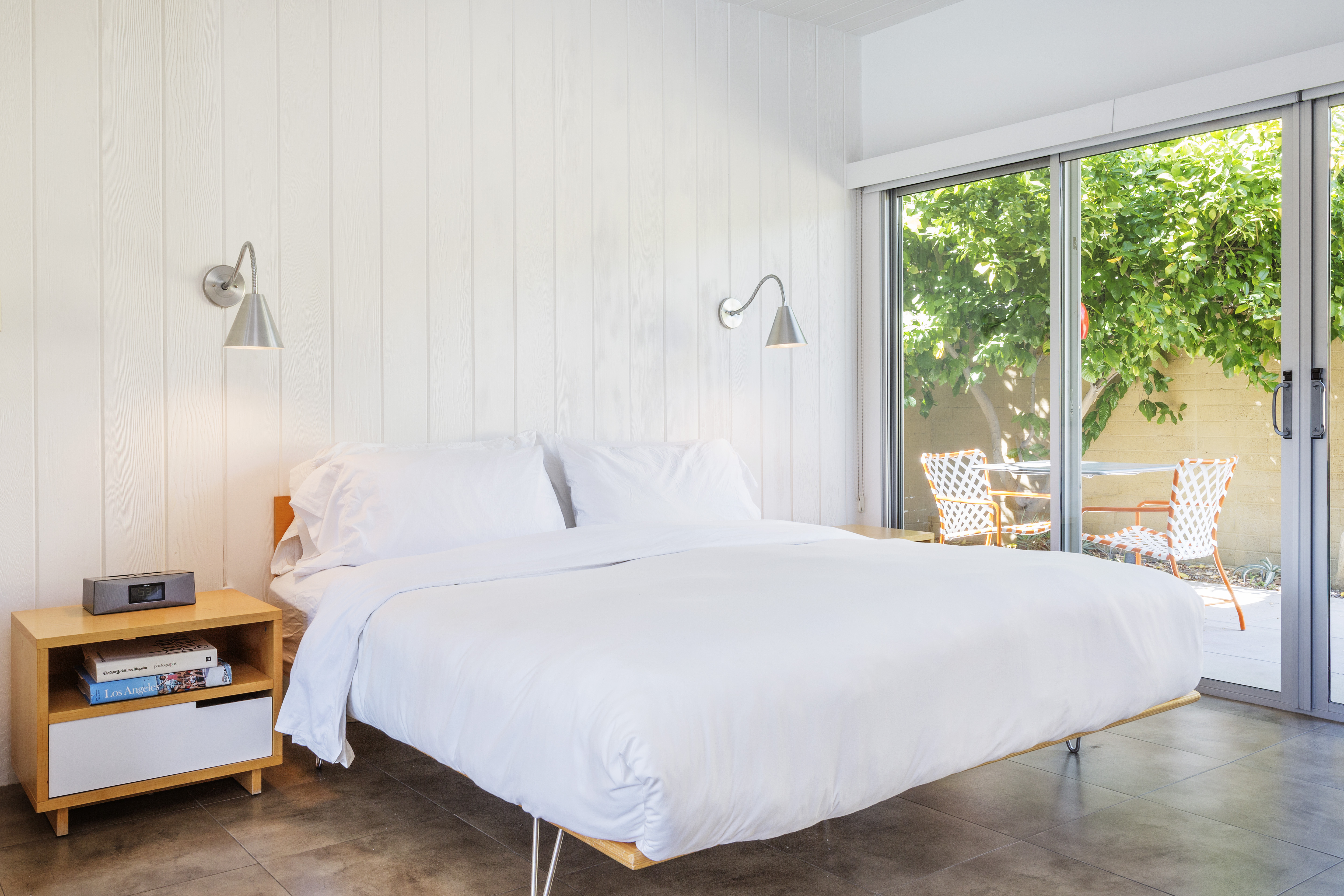 A hotel room with a bed, nightstand, and sliding glass door