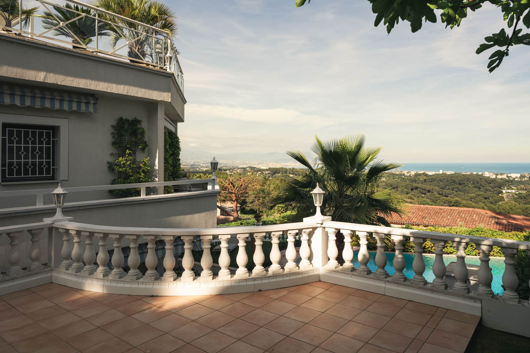Terrace balustrade framing palms, pool and sea view