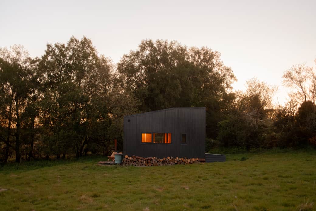 Tigin dark cabin glowing windows log store dusk