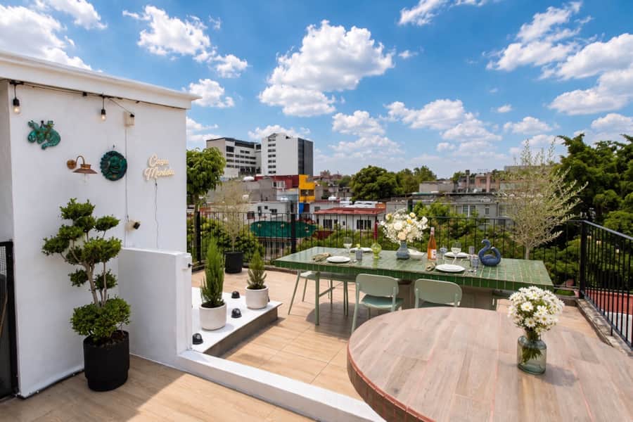 Terraza privada de Casa M&eacute;rida con mesa puesta sobre los techos de Roma Norte