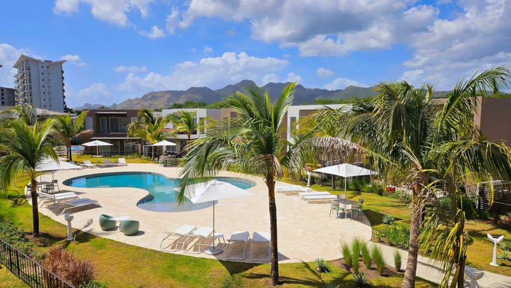 View of the pool from primary bedroom balcony with pergola and ceiling fan
