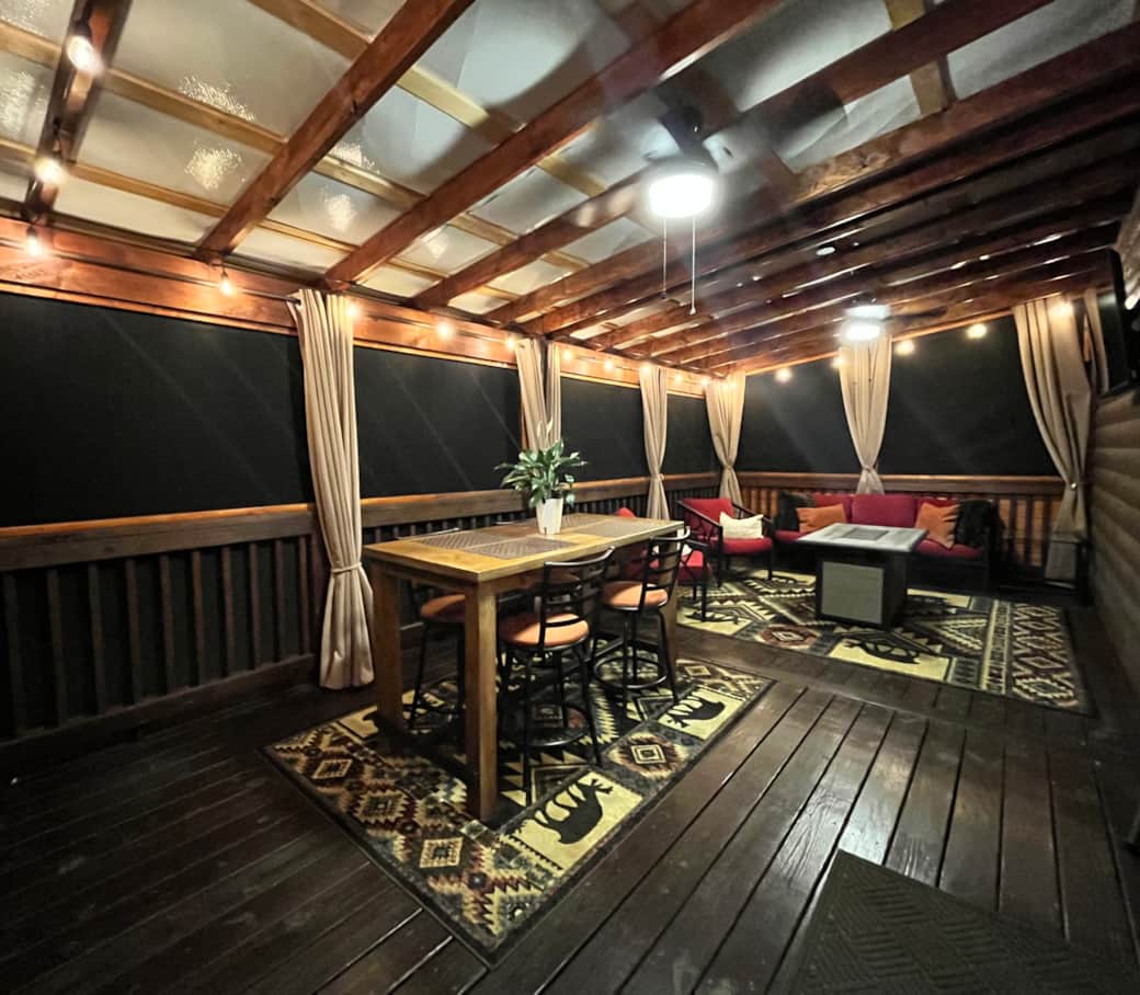 Screened-in back porch with dining space, seating and TV.