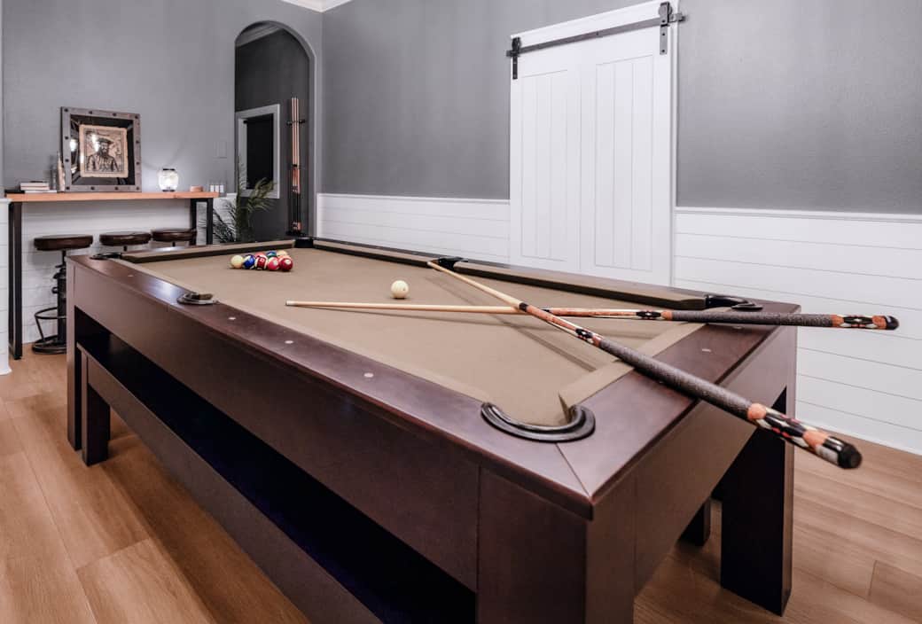 Daytime view of the pool table setup, with custom cues, cozy bar seating, and a nod to pirate lore. Daytime view of the pool table setup, with custom cues, cozy bar seating, and a nod to pirate lore.