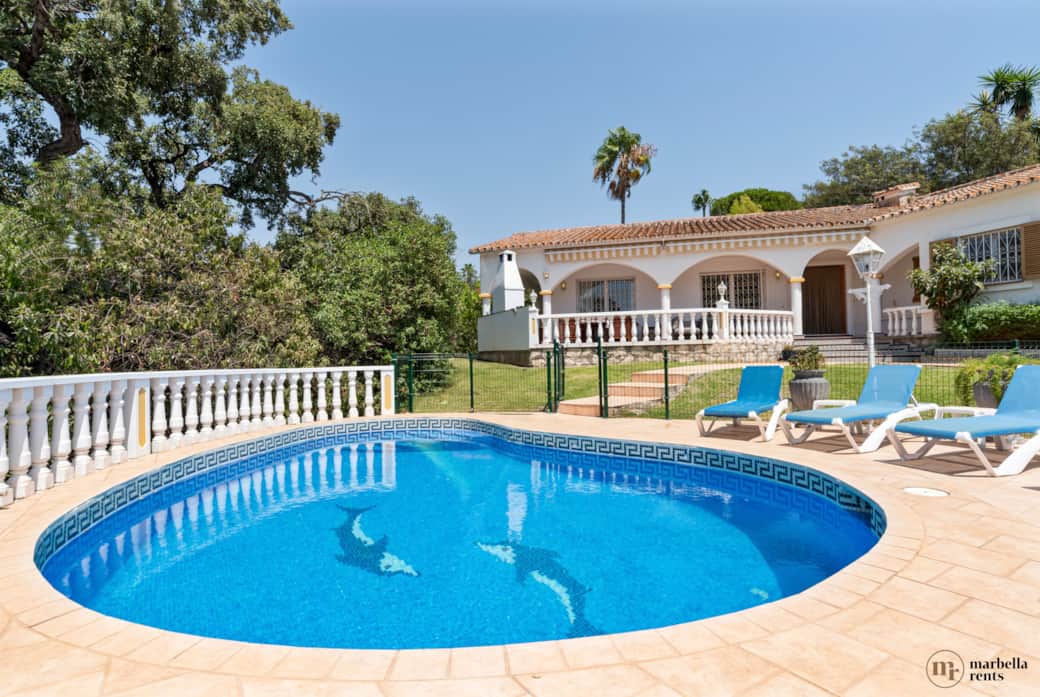 Fully fenced pool with sun loungers.