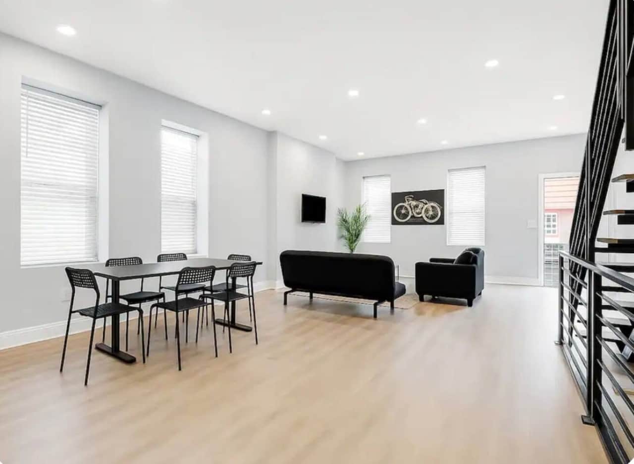 spacious living room featuring a large flat-screen TV and 3 comfortable futon sofa beds, providing plenty of seating during the day and extra sleeping space at night. The open-concept layout connects directly to the kitchen and dining area.