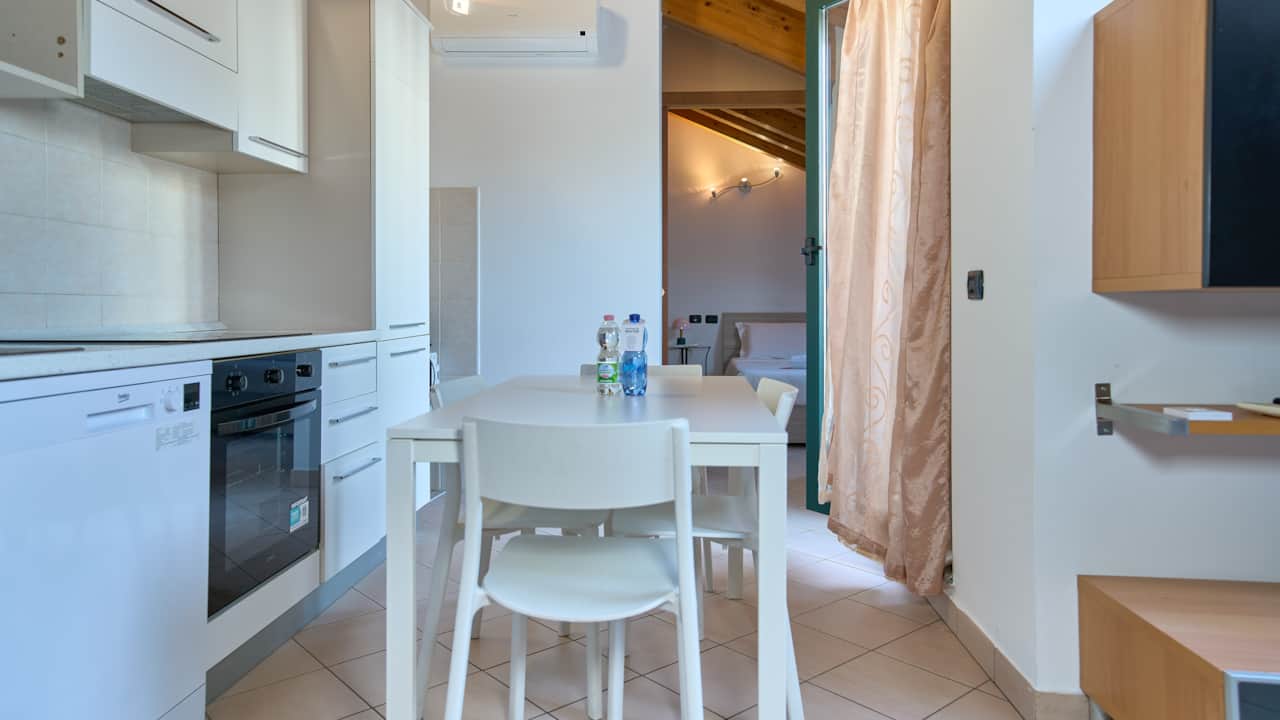 Mesa de comedor con sillas junto al horno y la cocina