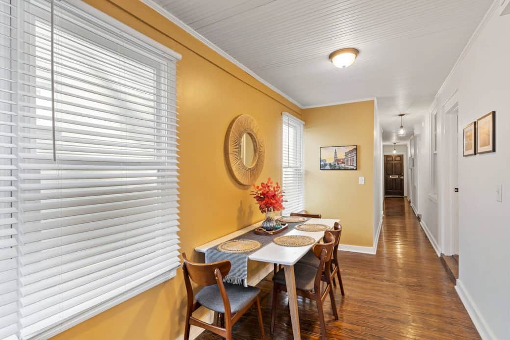 View from the entrance to bathroom #1 which has clawfoot tub and shower. Behind the camera is a stacked washer & dryer hidden behind a curtain. The hall leads to all 3 bedrooms on the right, bathroom #2 on the left and front entrance door.