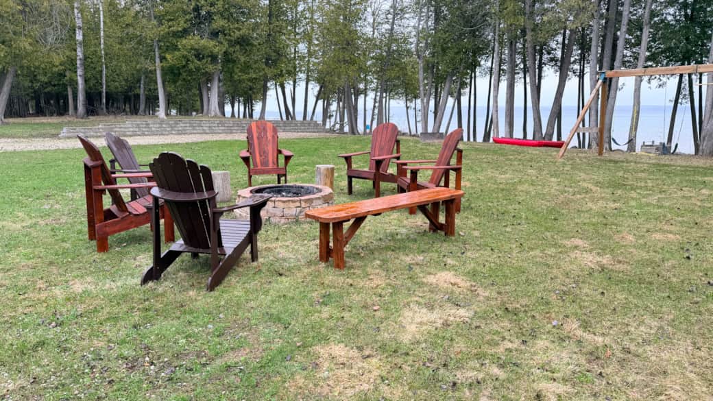 Spacious private property with firepit seating, surrounded by peaceful trees and water.