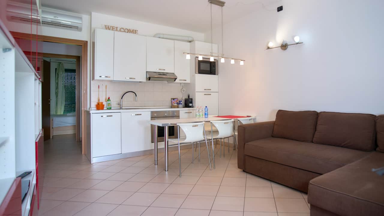 Kitchen with white units, table and brown sofa