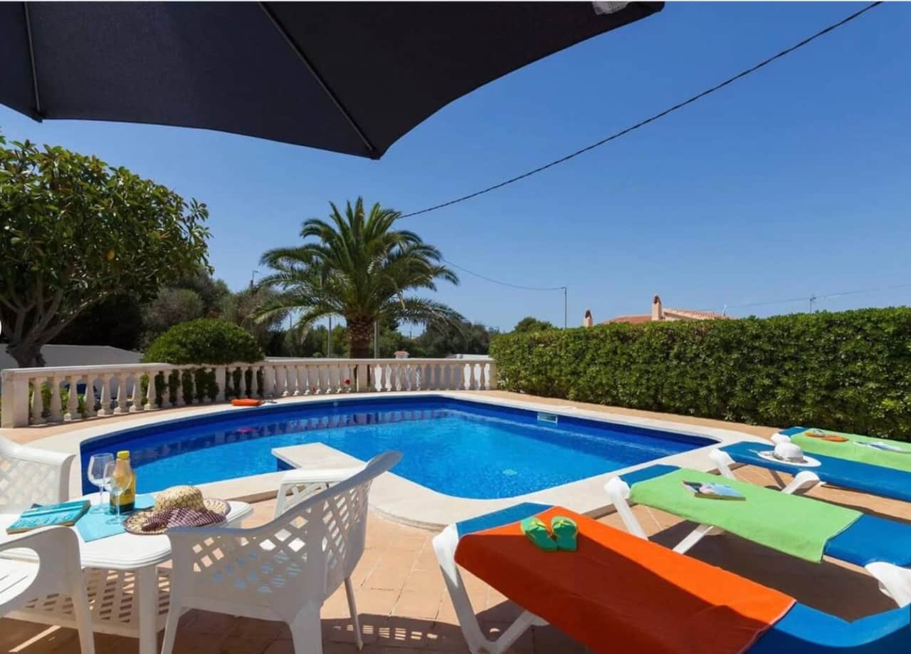 Pool and patio with sun loungers and umbrella
