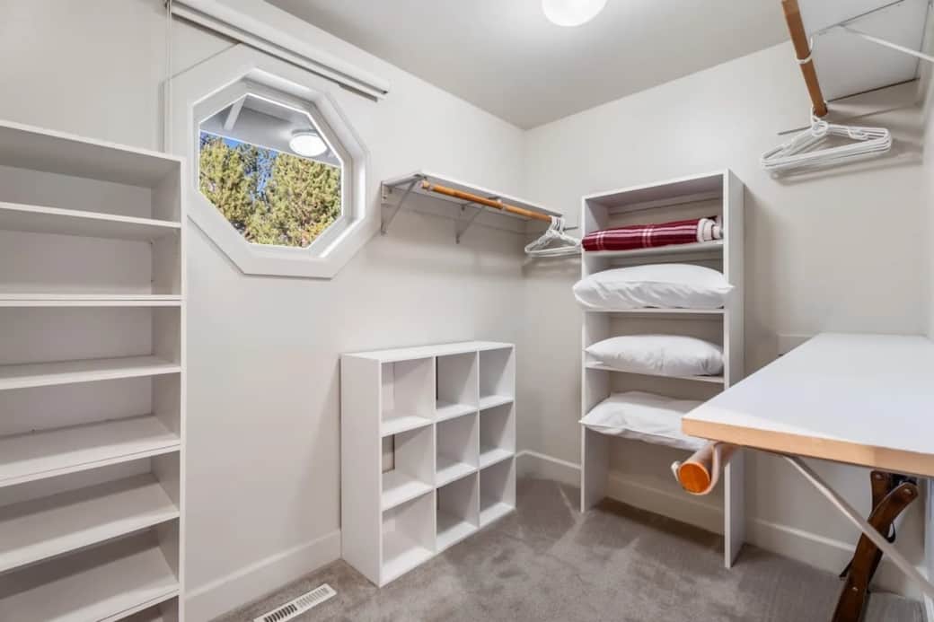 Large primary walk-in closet with extra pillows, blankets and iron