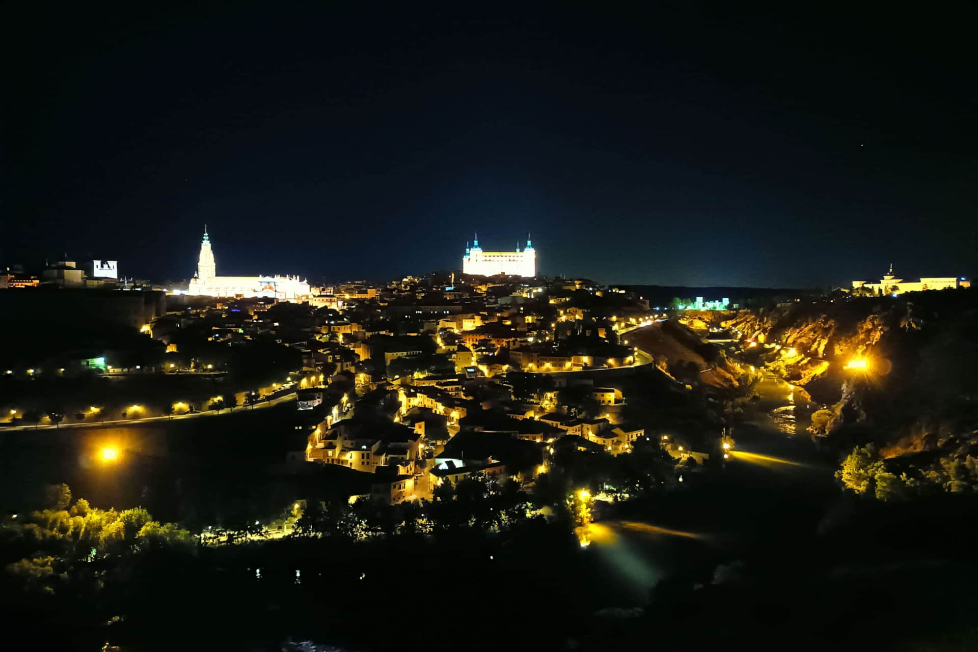 Alojamiento rural cerca de Toledo - La Casita de Ale, ideal para visitar Puy du Fou Vista nocturna de Toledo con iluminación cálida, destacando el Alcázar y la Catedral reflejados en el río