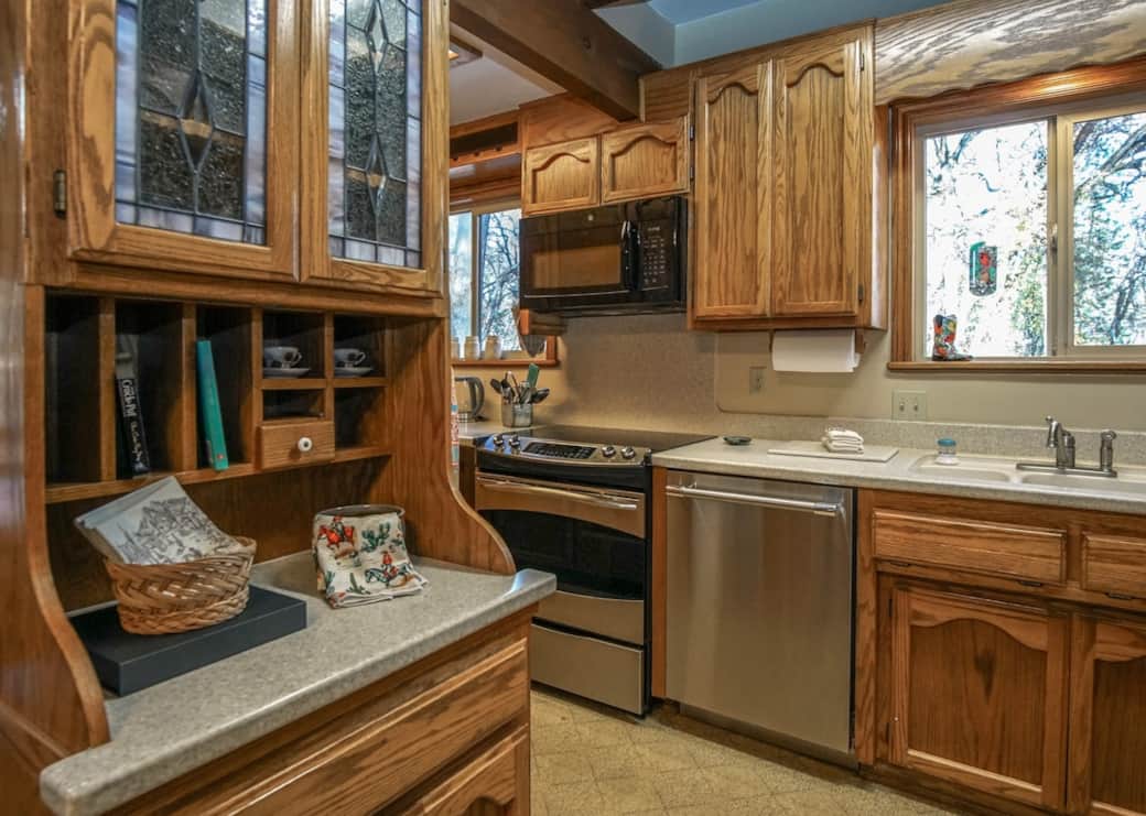 Warm, well-equipped kitchen with classic wood cabinetry, stainless appliances, and generous counter space—finished with charming rustic details and peaceful window views.