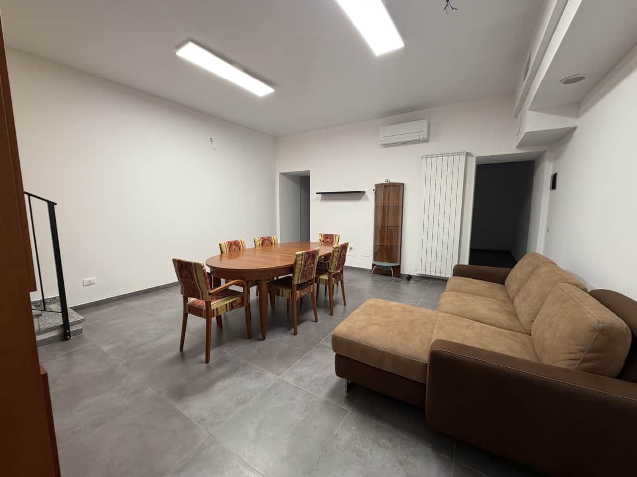 Sofá gris y mesa de comedor con sillas de madera