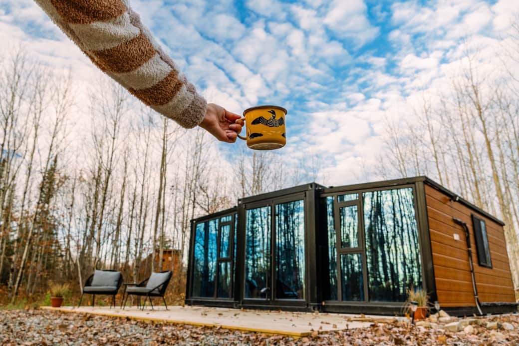 A tiny shipping container glass cabin amongst the trees