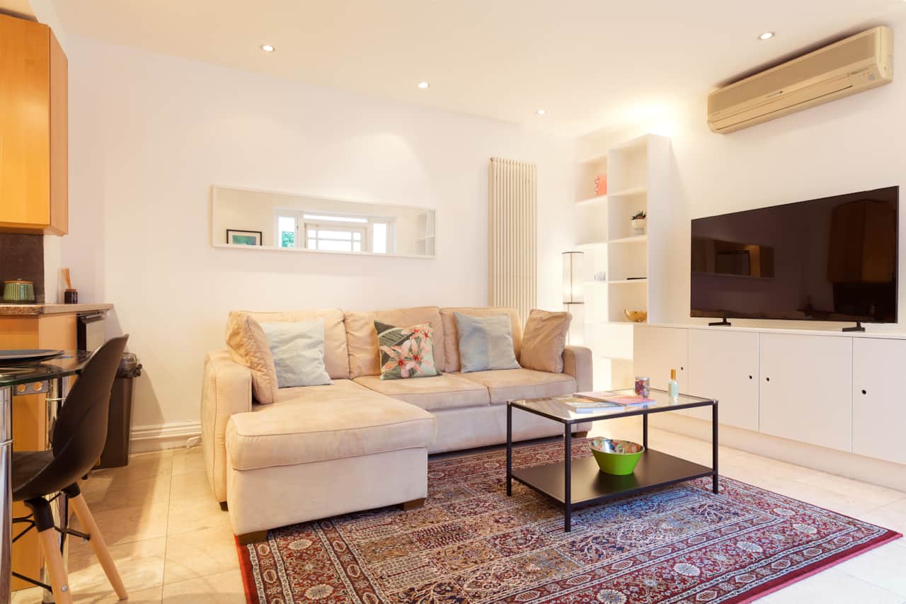 Bright living room with corner sofa, air conditioning and wall-mounted TV