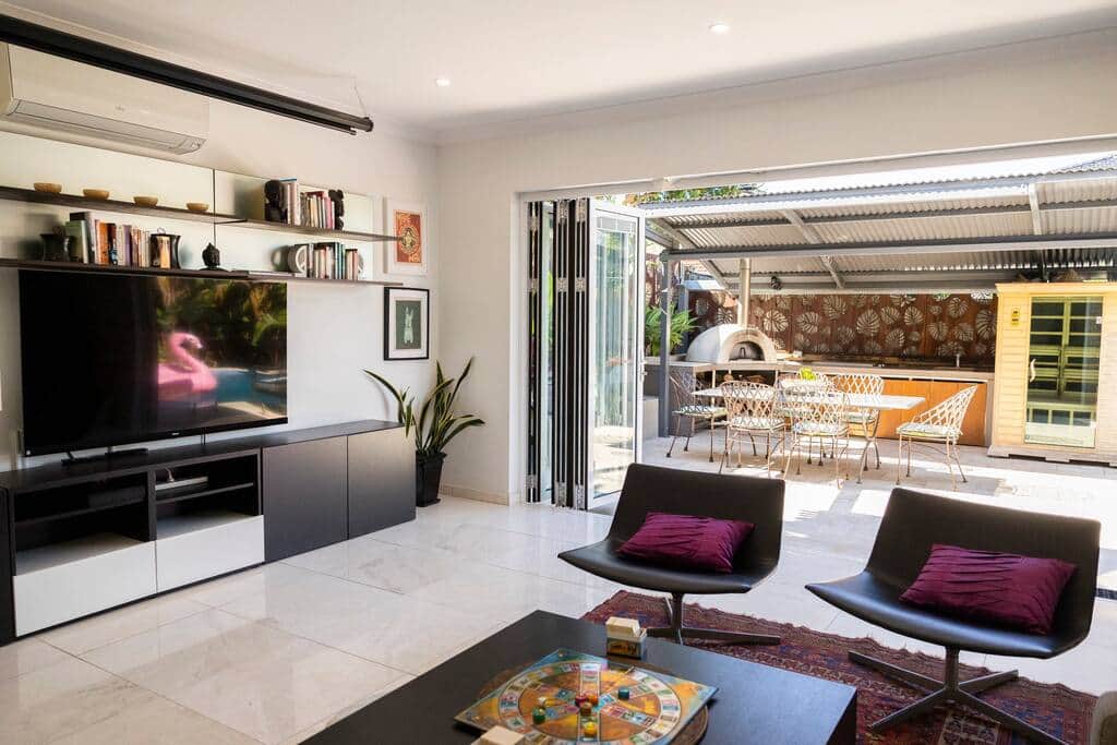 Lounge room opens to entertaining area with BBQ, outdoor setting and pool Lounge room opens to entertaining area with BBQ, outdoor setting and pool