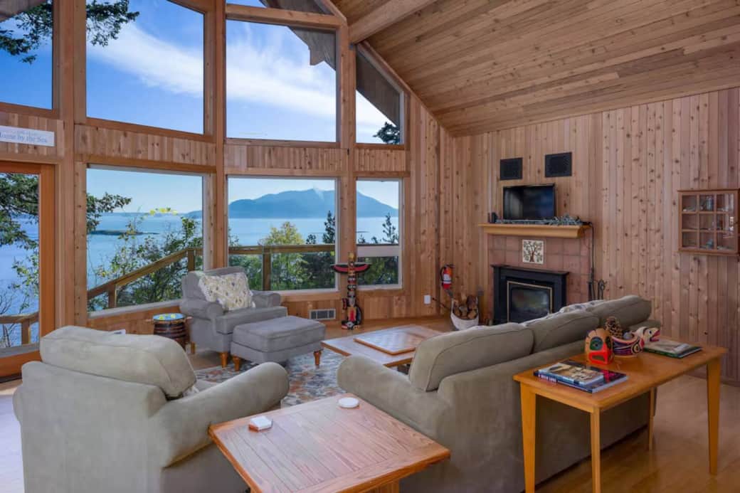 Soaring windows frame breathtaking views over Rosario Strait, creating a warm, light-filled living space perfect for relaxing by the fire or enjoying quiet island mornings. Soaring windows frame breathtaking views over Rosario Strait, creating a warm, light-filled living space perfect for relaxing by the fire or enjoying quiet island mornings.