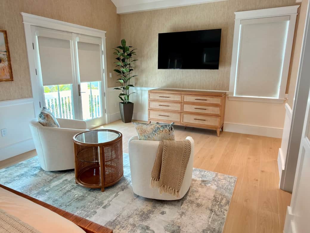 A spacious upstairs primary suite with a king bed, vaulted ceiling, smart TV, ceiling fan, and a pri