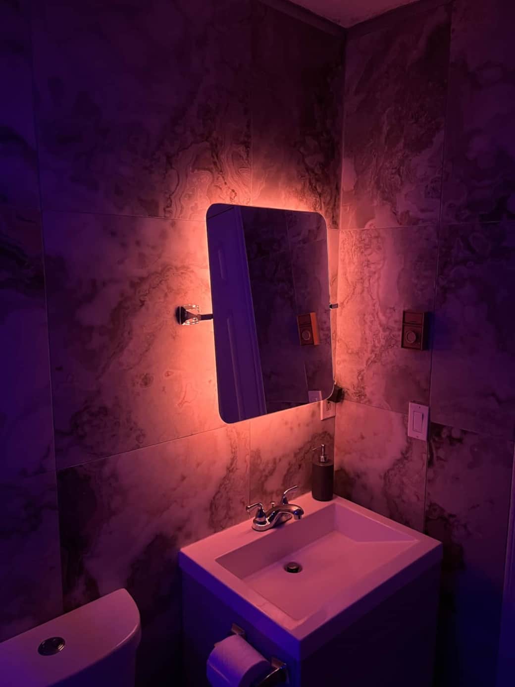 Totally reimagined bathroom covered in marble.  LED backlit mirror.
