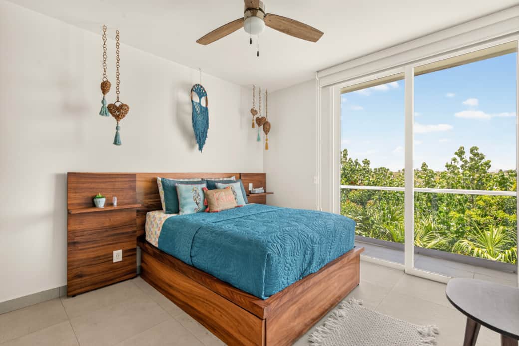 Queen bedroom with AC, a ceiling fan, blackout shades, bedside outlets, and a jungle-view balcony.