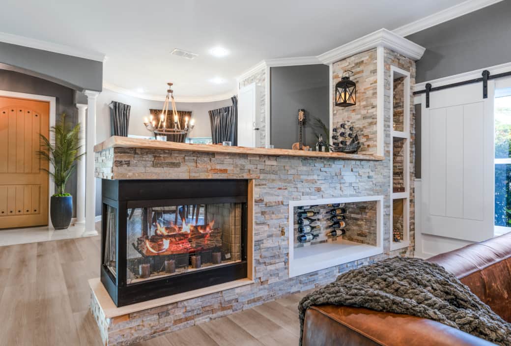 Stone-wrapped double-sided fireplace with live-edge bar top and built-in wine rack. Stone-wrapped double-sided fireplace with live-edge bar top and built-in wine rack.