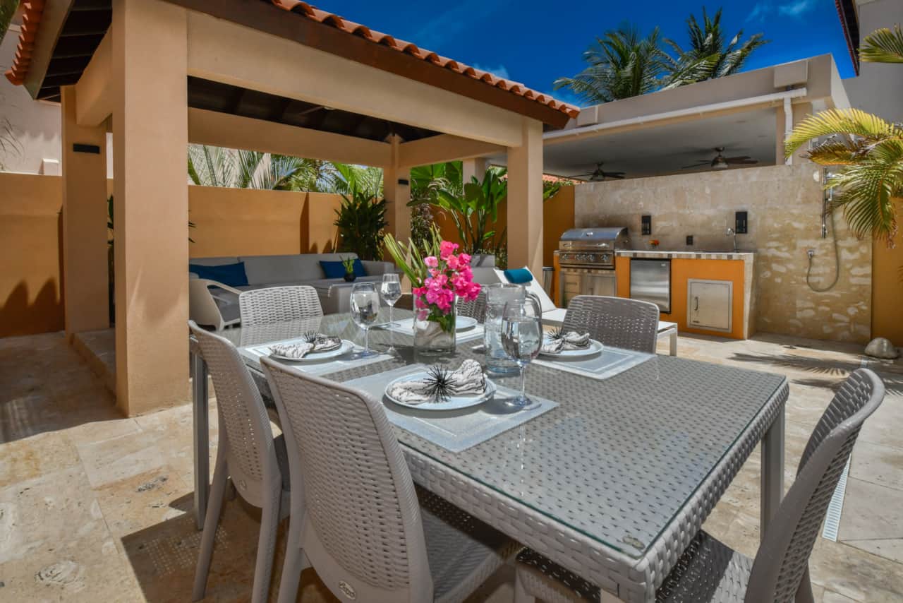 Outdoor dining table with seating for 6, BBQ, mini fridge, sink, and outdoor shower.