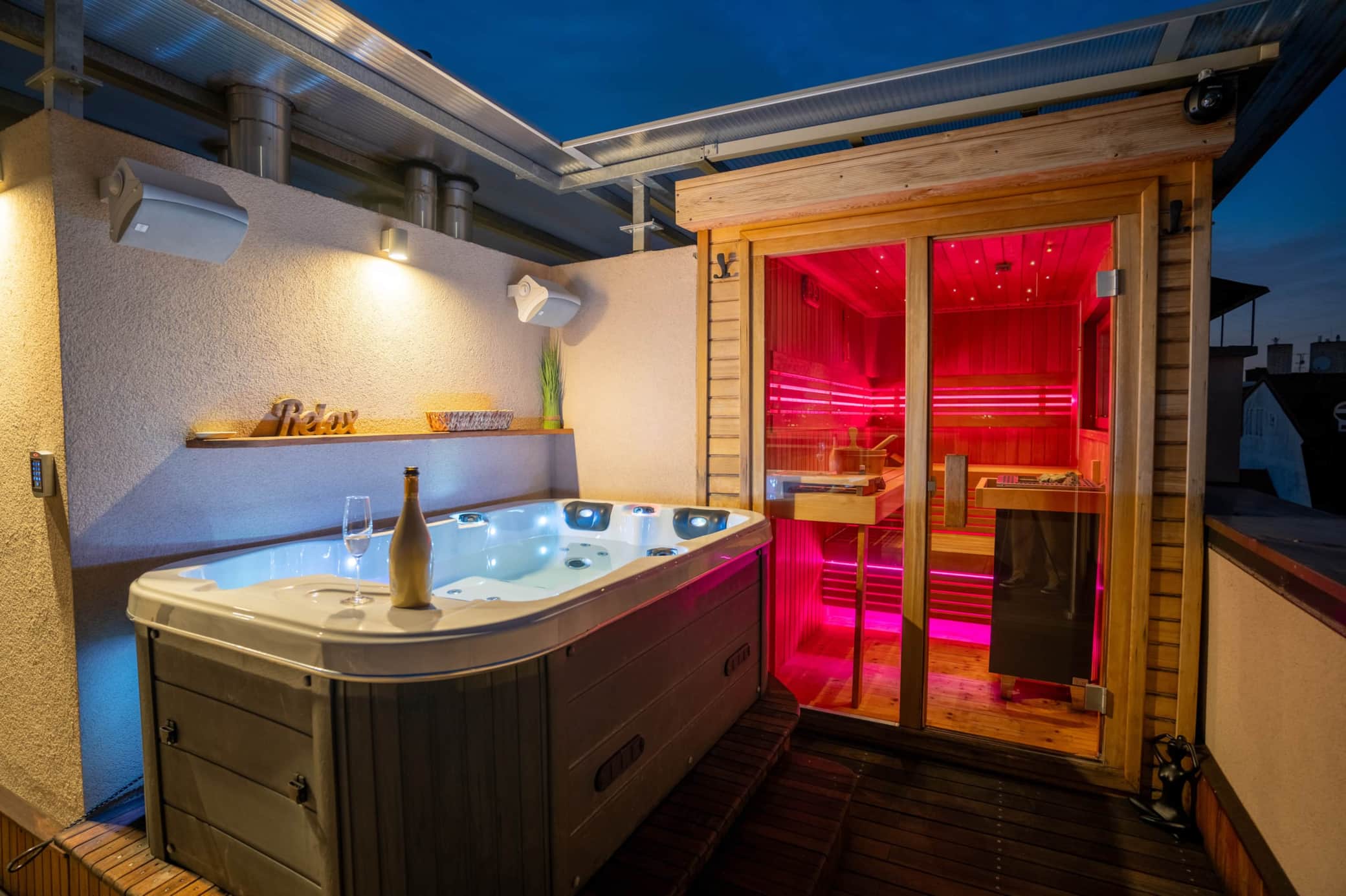 Private rooftop wellness terrace at night — hot tub and sauna