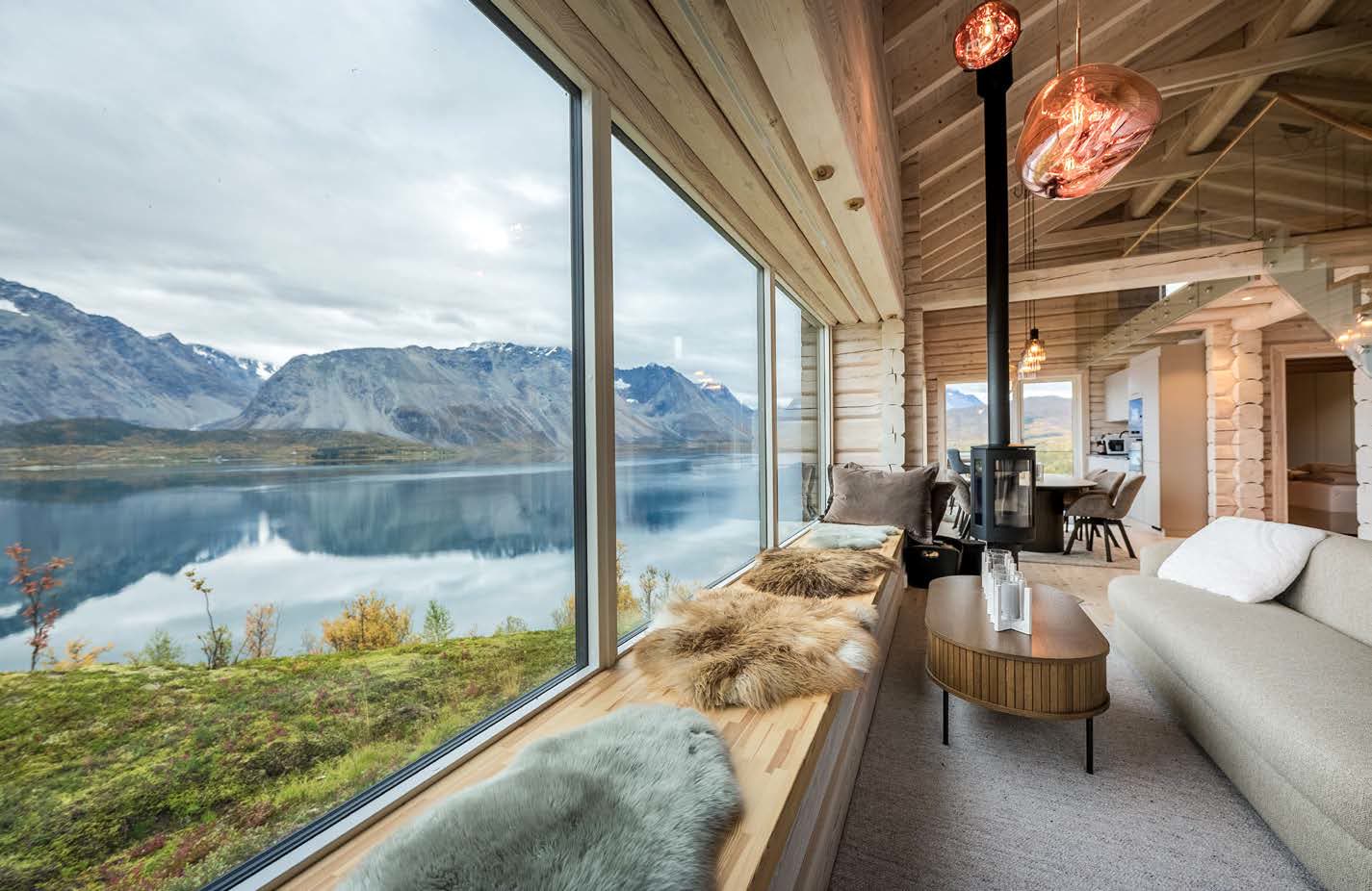 Living room with panoramic window towards the fjord, wood-burning stove and window seat